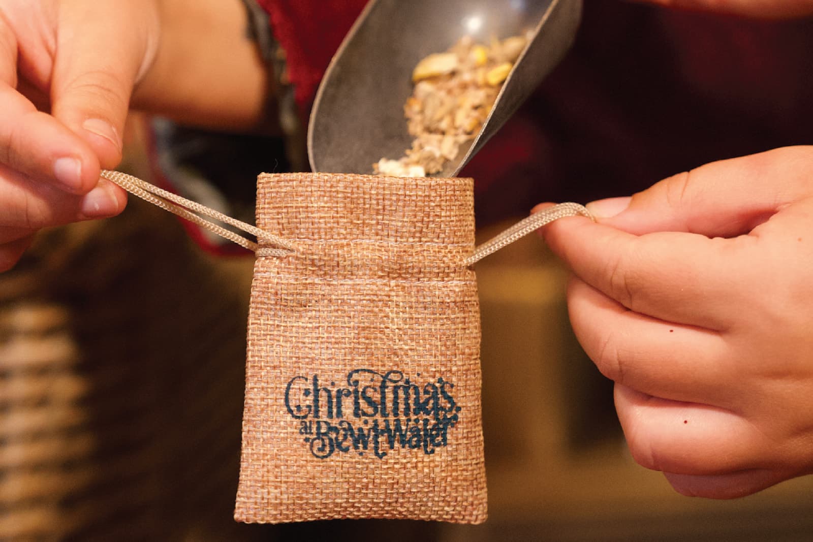 Reindeer food being scooped into a Christmas at Bewl Water hessian bag at Prancer's Pantry