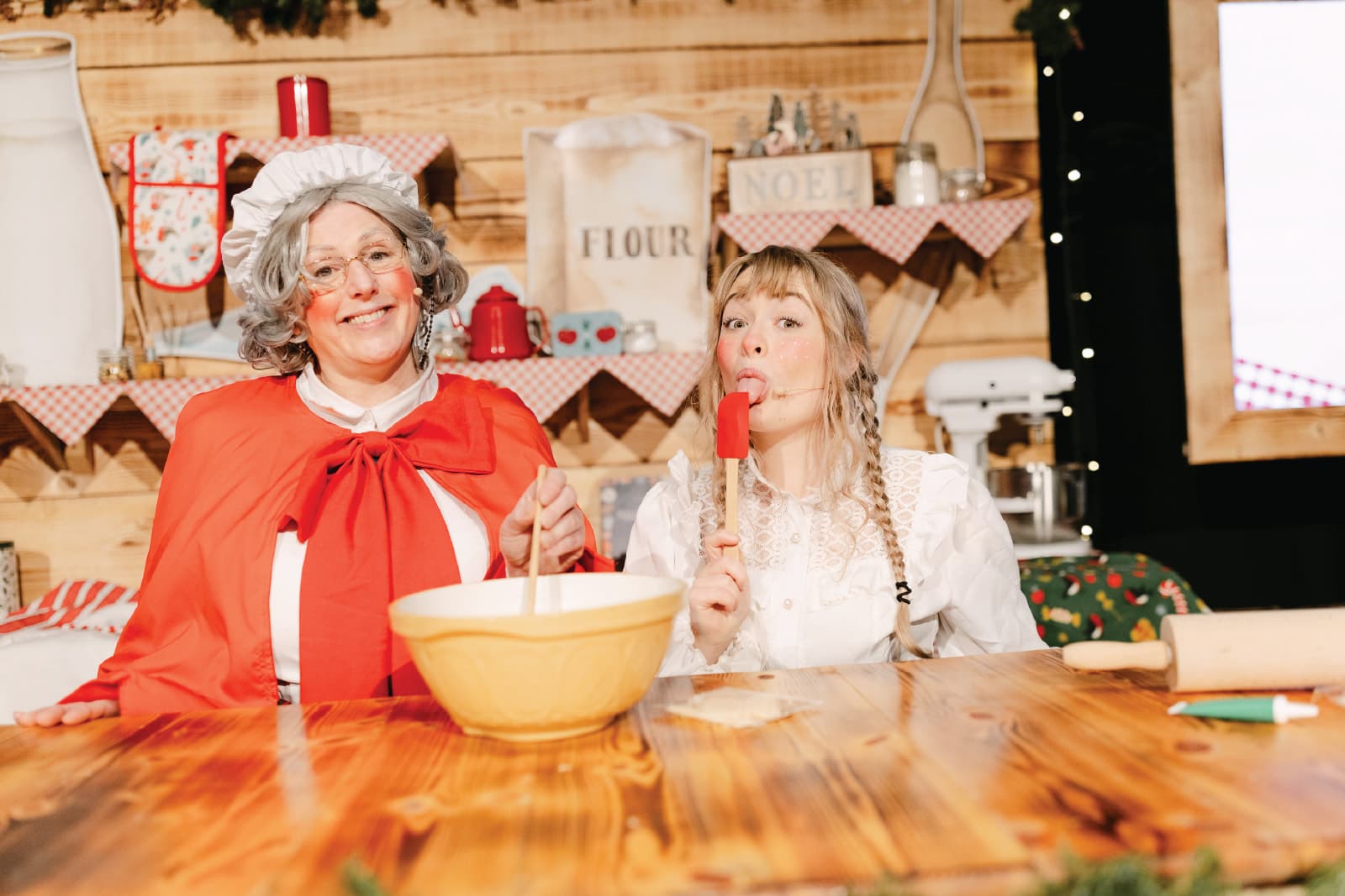 Rosemary and an elf mixing and tasting at the table in Rosemary's Bakery