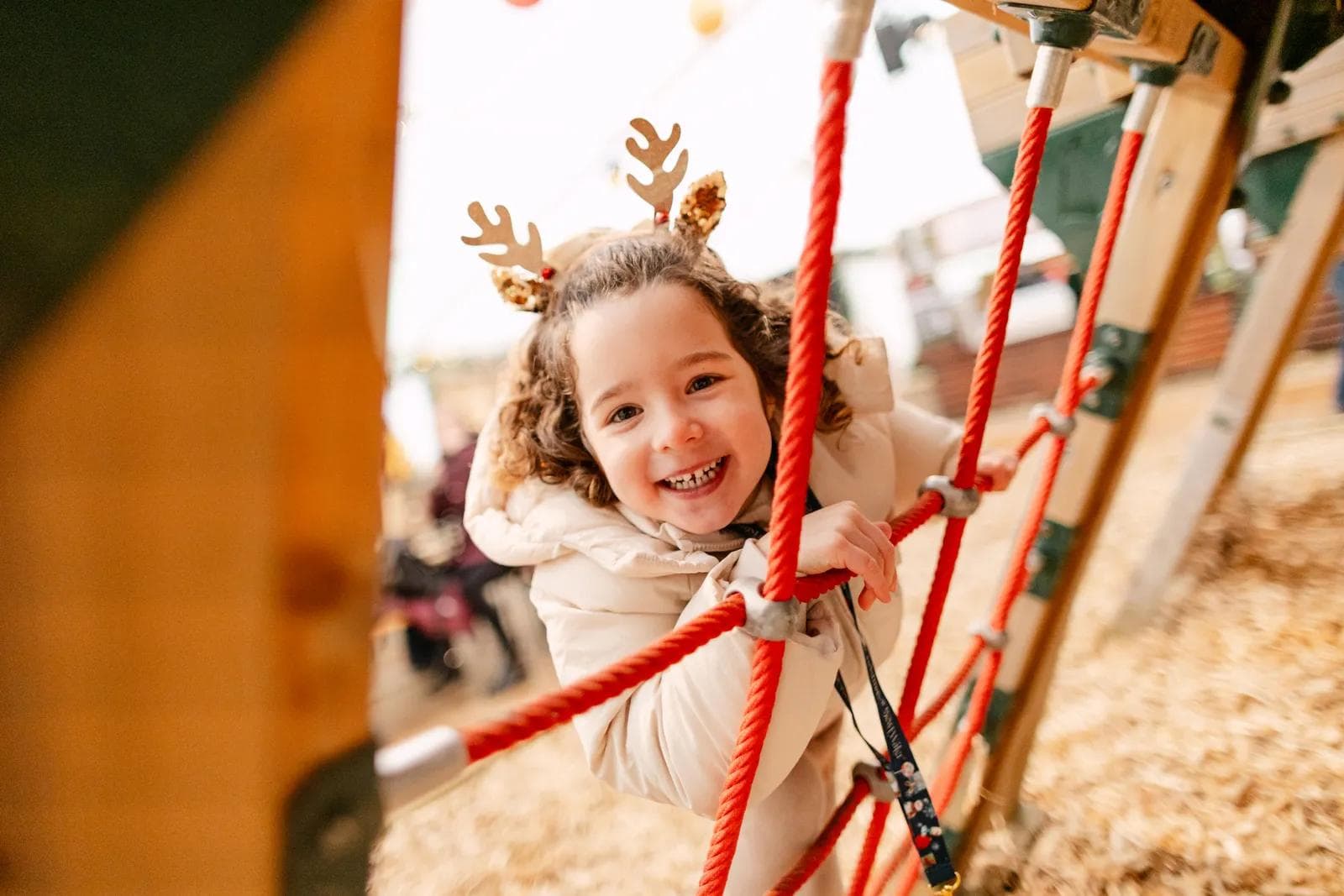 A smiling child on the rope climbing frame in the Candy Land play area