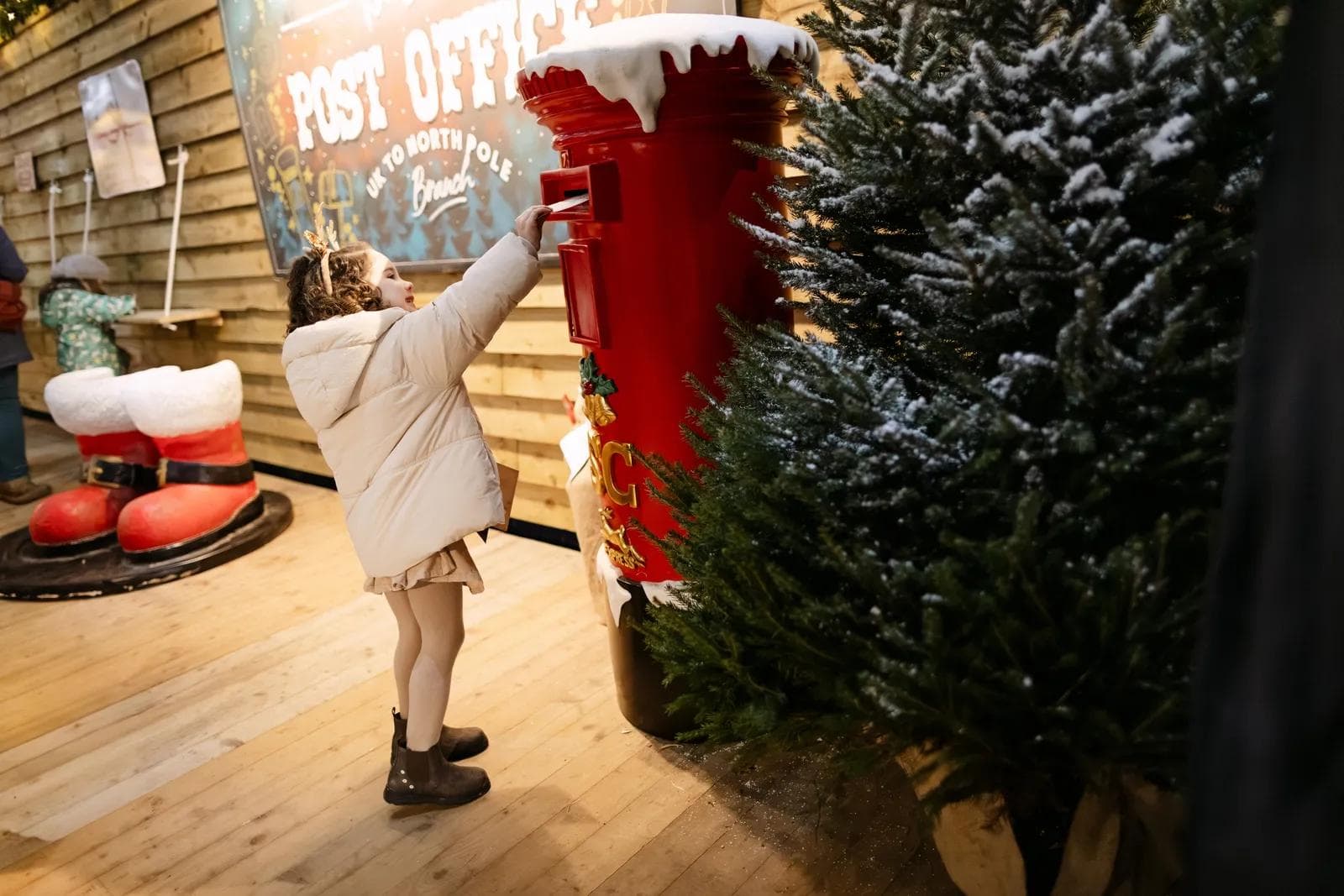 A child posting a letter to Santa in the red postbox at Dash's Post Office