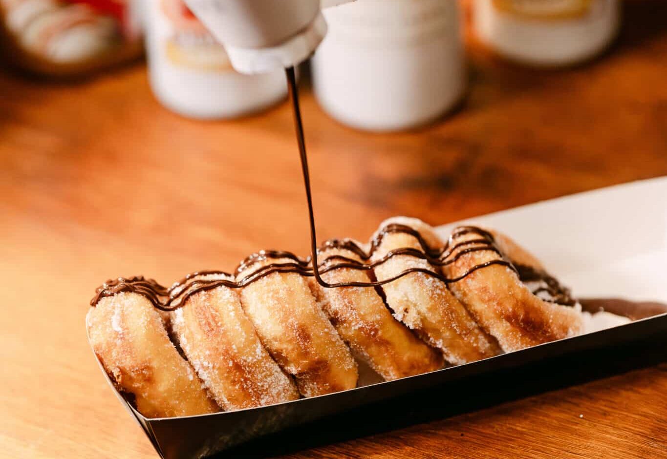 Fresh hot donuts being drizzled with chocolate at the Christmas at Bewl Water food court, a delicious festive treat at Kent’s family Christmas event.